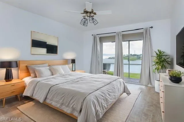 STAGED MASTER BEDROOM WITH ACCESS TO REAR LANAI, CEILING FAN AND LIGHT HARDWOOD LVP FLOORING