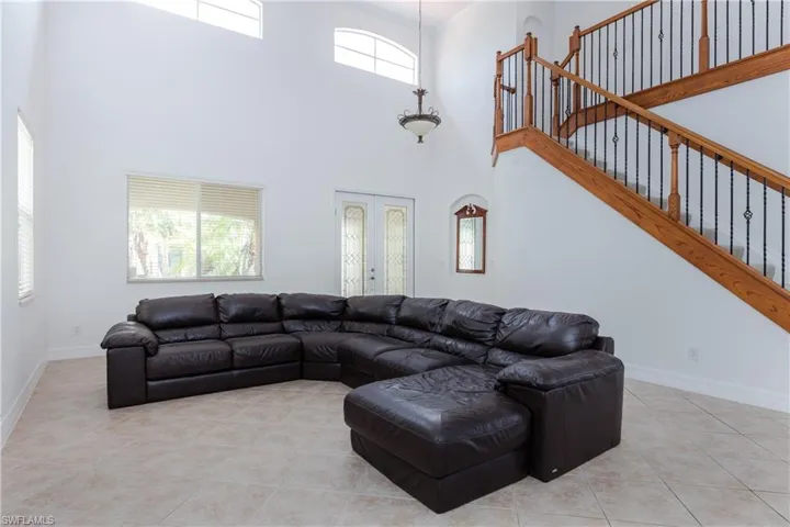 Living room with french doors, light tile patterned floors, and a high ceiling