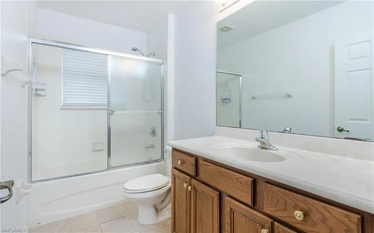 Upstairs bathroom with tile patterned flooring, shower / bath combination with glass door, vanity, and toilet