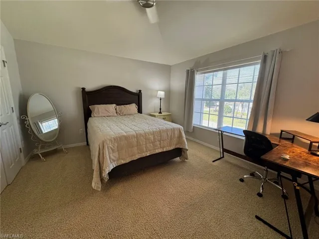 Carpeted bedroom featuring ceiling fan and lofted ceiling