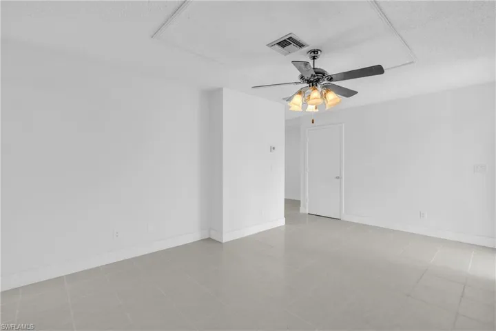 Empty room featuring attic access, a textured ceiling, and ceiling fan