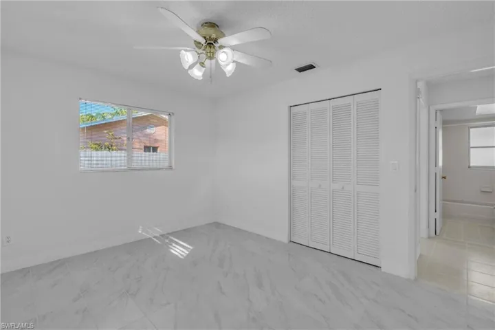 Unfurnished bedroom featuring a closet, a ceiling fan, and light marble finish flooring