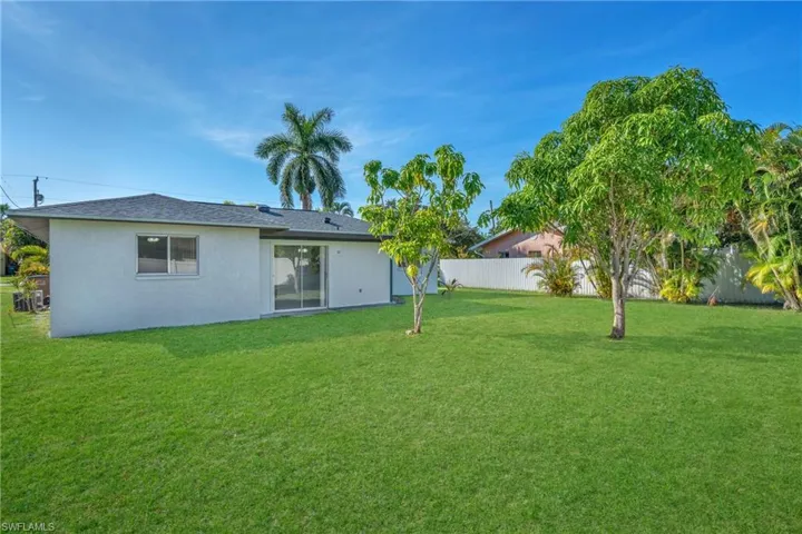 Back of property with a fenced backyard, stucco siding, and roof with shingles