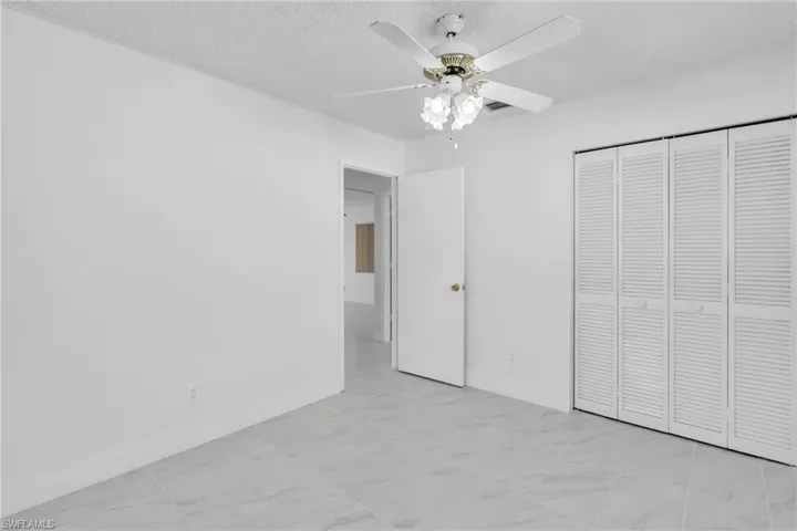 Unfurnished bedroom featuring a textured ceiling, ceiling fan, and a closet