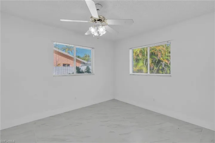 Empty room with plenty of natural light, a textured ceiling, and ceiling fan