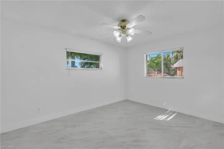 Unfurnished room with a textured ceiling, light marble finish floors, and a ceiling fan