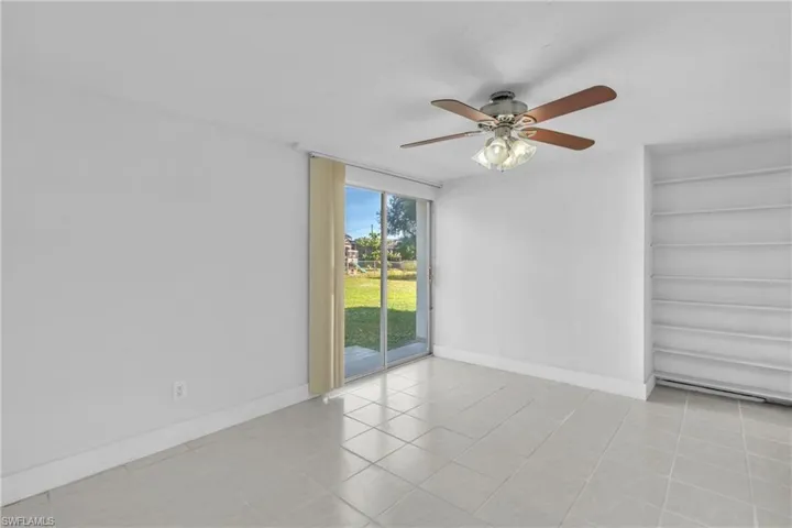 Empty room with built in shelves, a ceiling fan, and light tile patterned floors