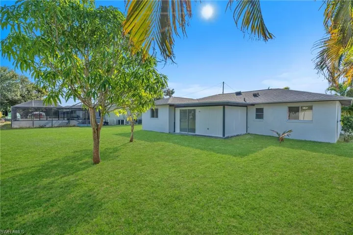 Back of house with a lawn and stucco siding
