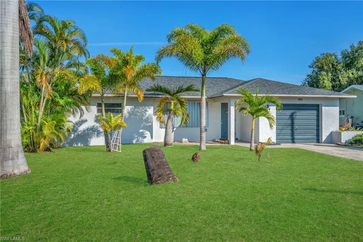 Ranch-style house with a front yard, an attached garage, stucco siding, driveway, and a shingled roof