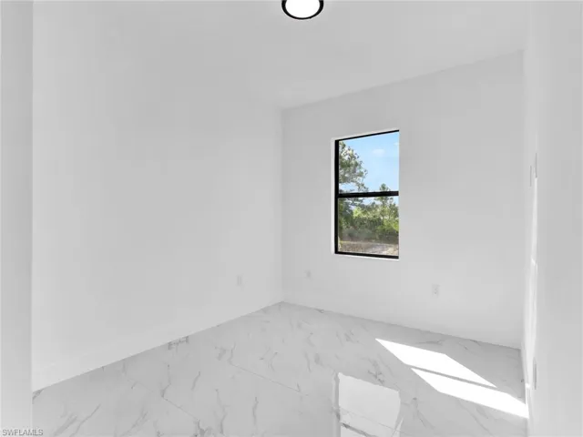 Empty room featuring light marble finish flooring and baseboards