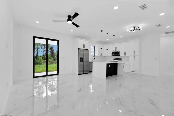 Kitchen with a kitchen island, recessed lighting, light marble finish floors, appliances with stainless steel finishes, and white cabinets