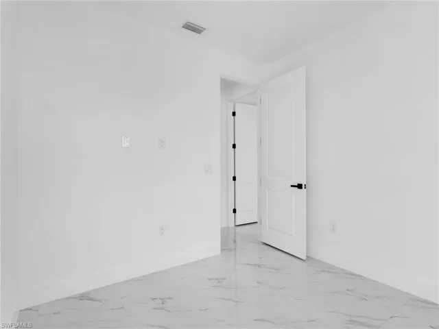 Unfurnished room featuring baseboards and light marble finish floors