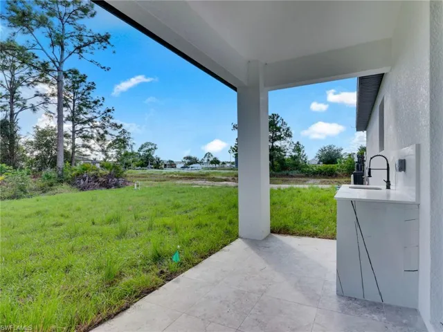 View of grassy yard featuring a patio area and a sink