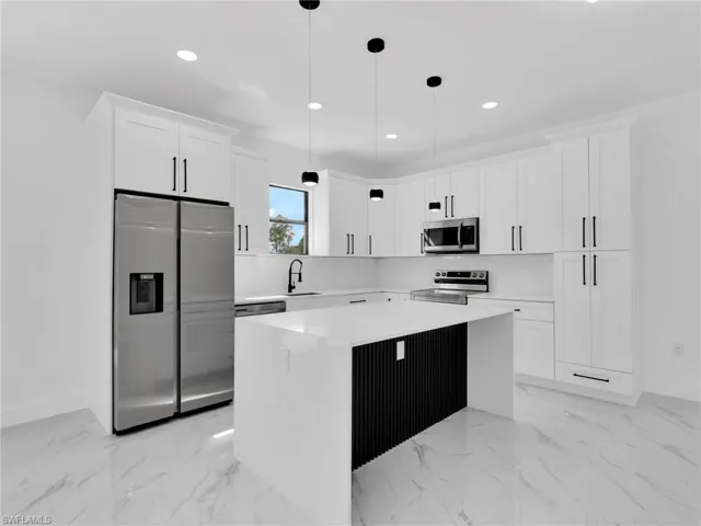 Kitchen featuring stainless steel appliances, white cabinetry, a kitchen island, recessed lighting, and decorative light fixtures