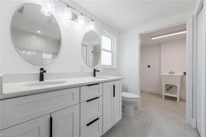 Master Bathroom featuring double vanity, walk-in shower and access to laundry area