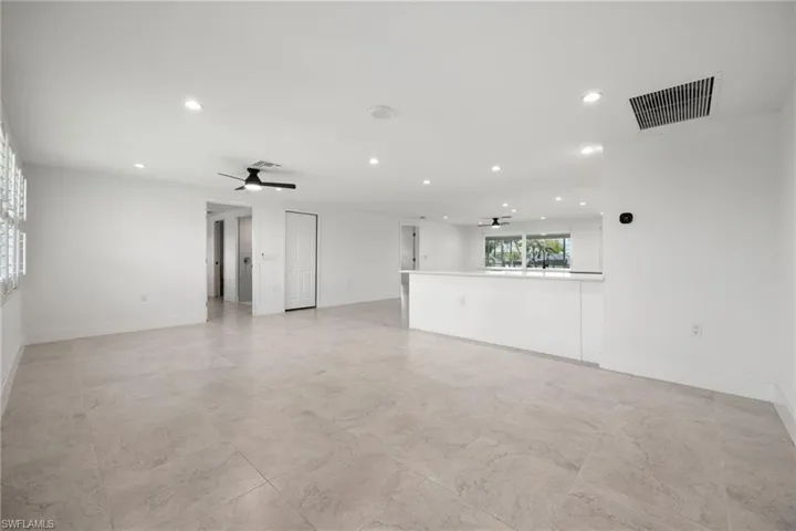 Spacious open-concept living room as you step in from the front door, featuring neutral tile flooring, recessed lighting, and a seamless flow into the kitchen and dining areas.