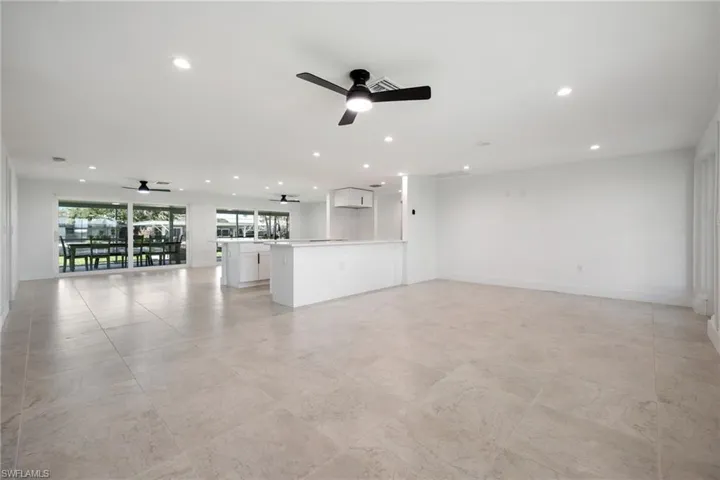 Open living area with tile floors, modern finishes, and sliding glass doors to the lanai and water views.