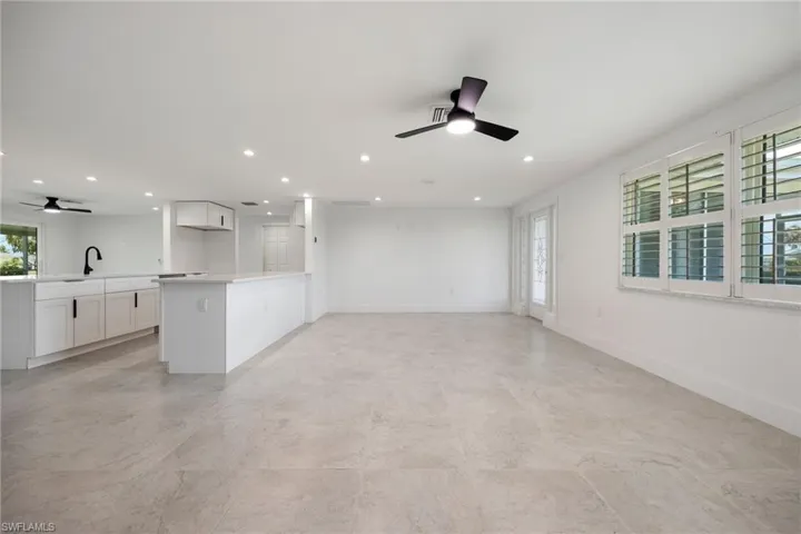 Bright open living space with tile floors, plantation shutters, and direct flow to the kitchen