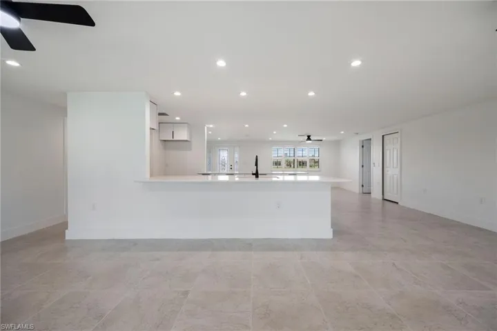 Kitchen with a ceiling fan, recessed lighting, white cabinets, a peninsula, and light stone countertops