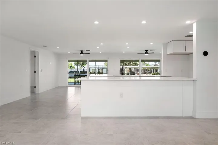 Modern kitchen with a large peninsula, open sightlines to the living area, and sliding glass doors showcasing waterfront views.