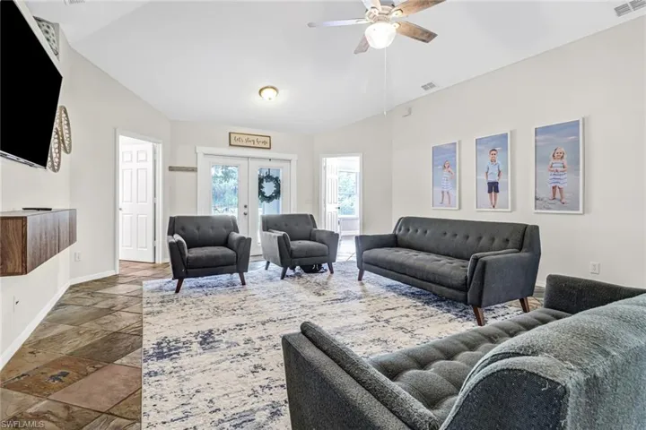 Living room with tile flooring, ceiling fan, french doors, and lofted ceiling
