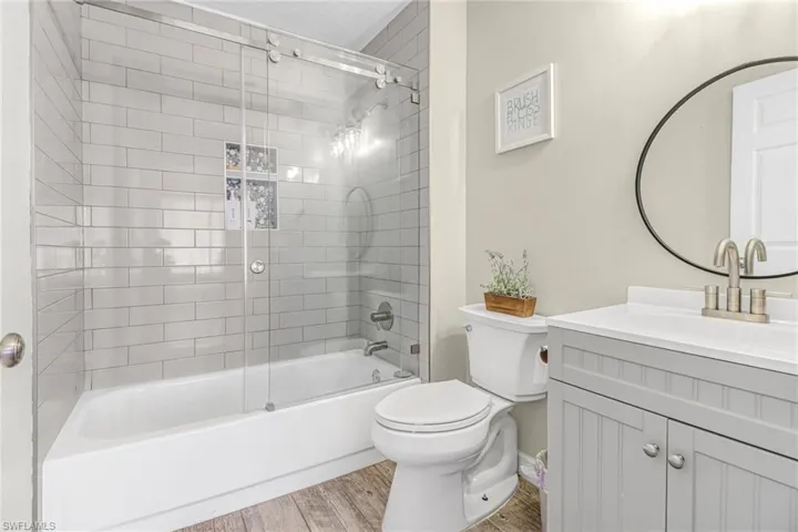 Full bathroom featuring tiled shower / bath, hardwood / wood-style floors, toilet, and vanity