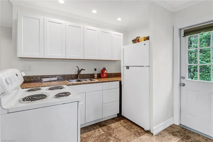 Guest house kitchen featuring sink, ornamental molding, white appliances, and light tile floors