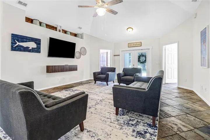 Living room with tile floors, french doors, ceiling fan, and vaulted ceiling