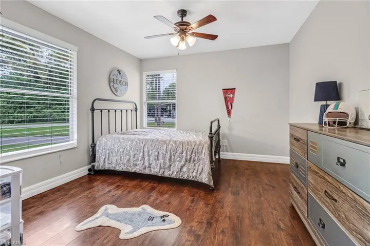 Bedroom with dark hardwood / wood-style floors, multiple windows, and ceiling fan