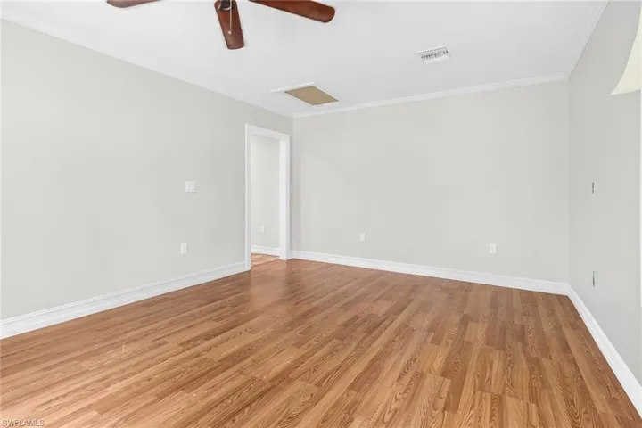 Spare room with ornamental molding, ceiling fan, and light wood-type flooring