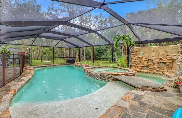 View of pool with glass enclosure and an in ground hot tub