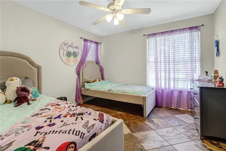 Bedroom with tile floors, multiple windows, and ceiling fan