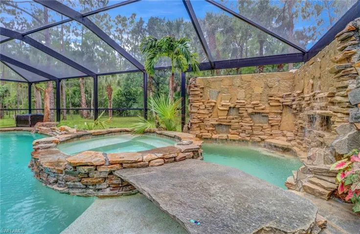 View of swimming pool featuring a lanai and an in ground hot tub