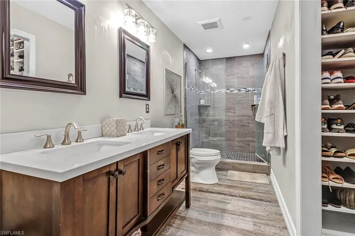 Bathroom with a shower with door, toilet, hardwood / wood-style flooring, and double sink vanity