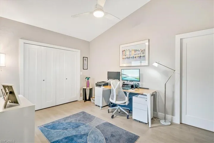 Office with light wood-type flooring, vaulted ceiling, and ceiling fan