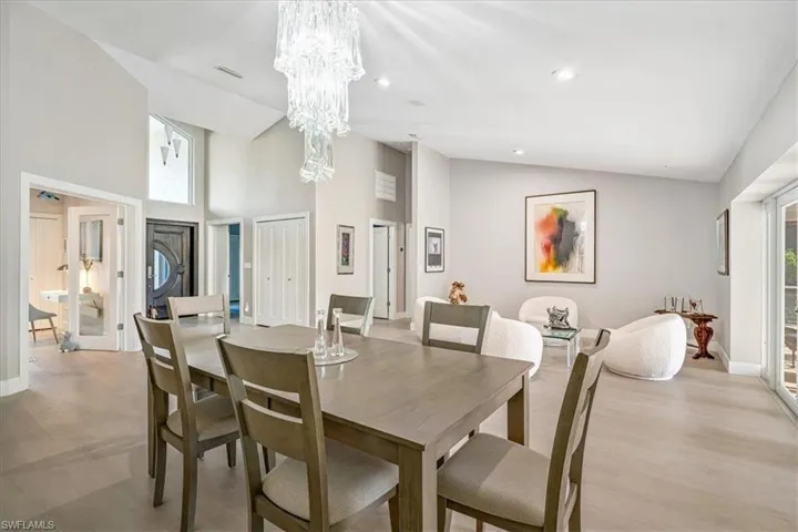 Dining room featuring high vaulted ceiling, light wood-style flooring, recessed lighting, and a chandelier
