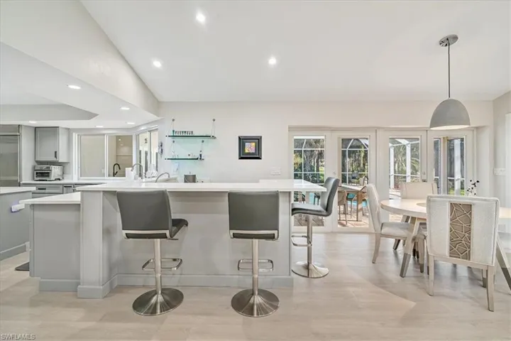 Kitchen with recessed lighting, lofted ceiling, decorative light fixtures, a kitchen breakfast bar, and gray cabinetry