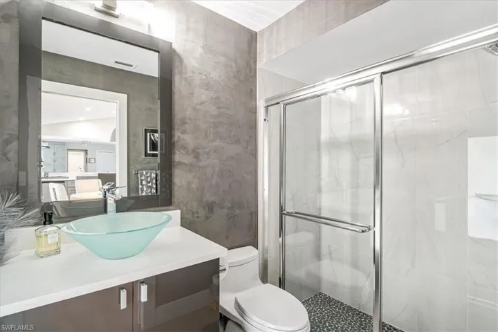 Bathroom featuring vanity and a marble finish shower