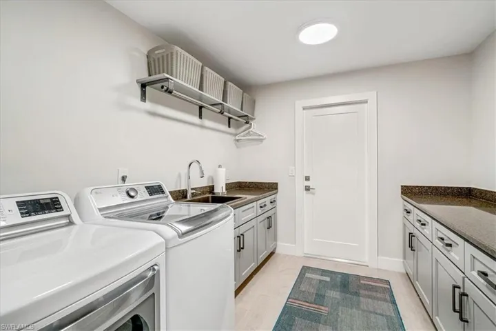 Laundry area with cabinet space, washing machine and clothes dryer, and light wood-type flooring