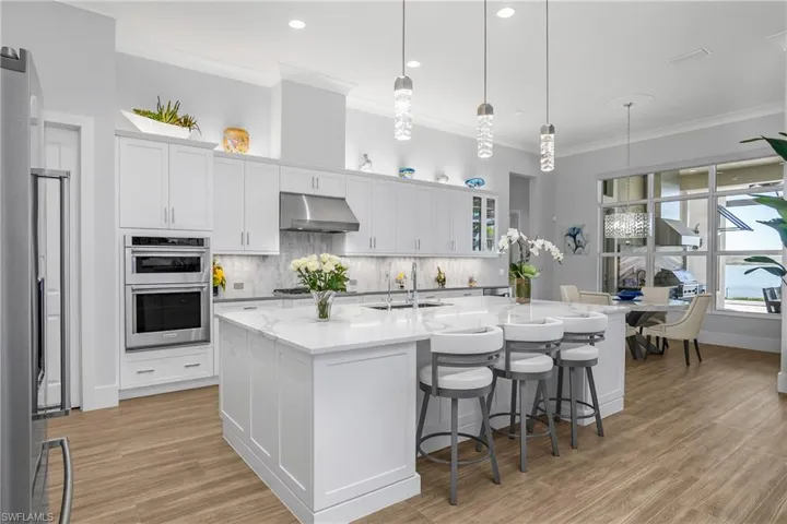 This kitchen is a chef's dream featuring an oversized island with additional storage cabinetry, natural gas cooktop, over/under cabinet lighting, and a spacious walk-in pantry.