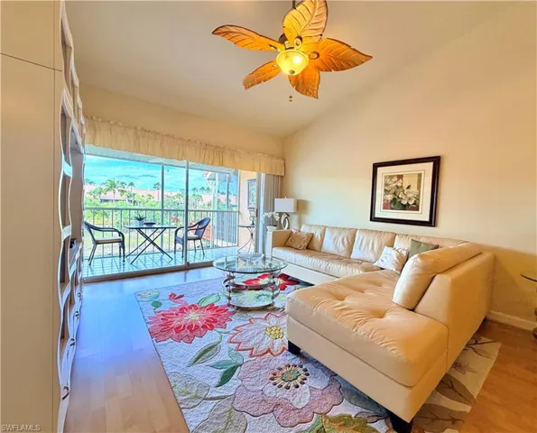 Living room featuring a ceiling fan, vaulted ceiling, and light wood finished floors
