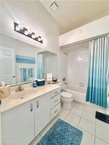 Bathroom featuring shower / bath combo, vanity, and light tile patterned floors