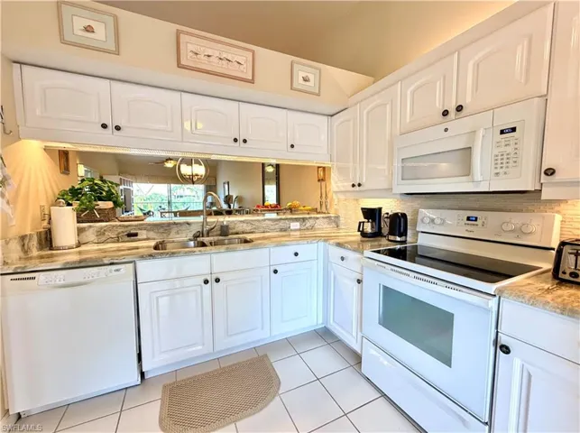 Kitchen with white appliances, white cabinets, and light tile patterned floors