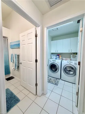 Laundry room featuring cabinet space, light tile patterned floors, and washing machine and clothes dryer