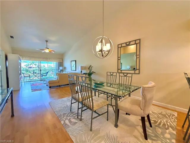 Dining space with ceiling fan, vaulted ceiling, wood finished floors, and hanging lights