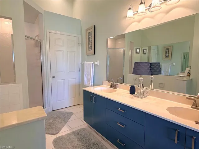 Full bathroom featuring a stall shower, double vanity, and light tile patterned flooring