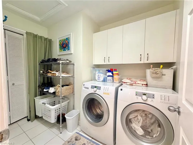 Laundry area featuring cabinet space, separate washer and dryer, and light tile patterned flooring