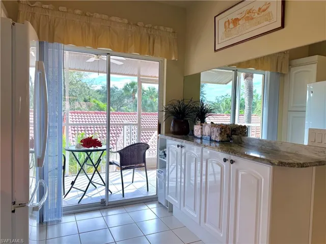 Kitchen, dark stone countertops, white cabinetry, light tile patterned floors