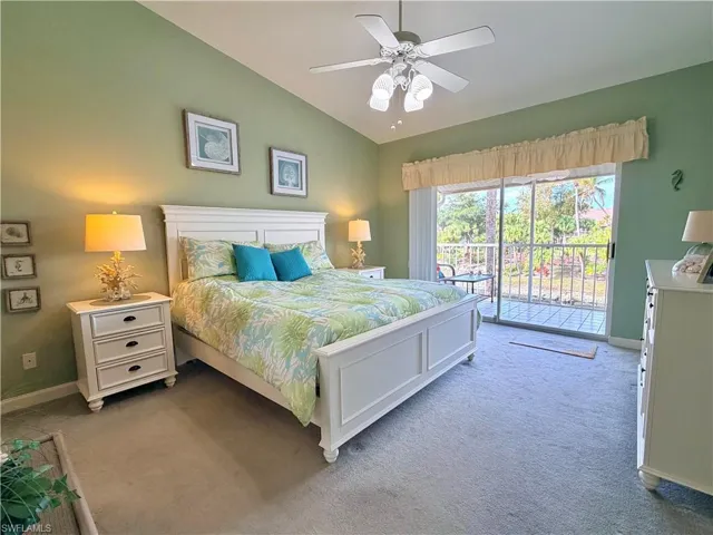 Carpeted bedroom with access to exterior, vaulted ceiling, and a ceiling fan