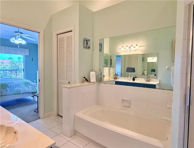 Bathroom with double vanity, a closet, a garden tub, light tile patterned floors, and ensuite bathroom